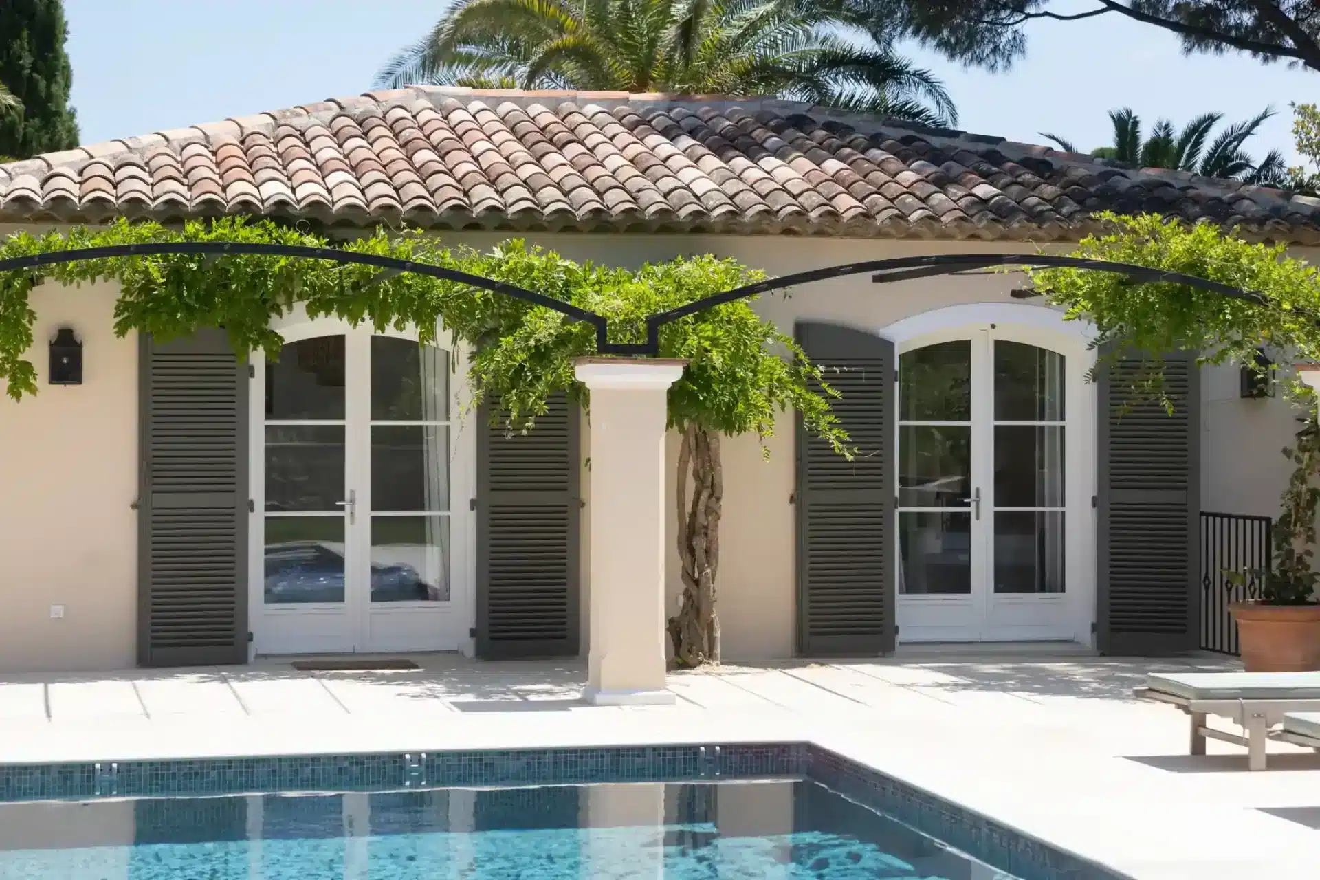 Porte-fenêtre cintrée bois traditionnelle Reveau avec volets battants sur terrasse de villa